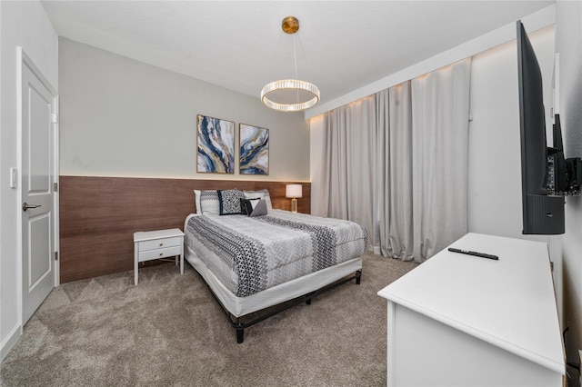 bedroom with wooden walls, a wainscoted wall, and carpet floors