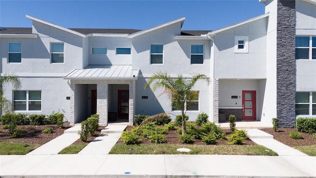 multi unit property with a standing seam roof, stucco siding, and metal roof