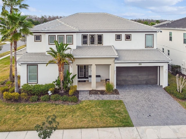 view of front of property with decorative driveway, a front lawn, stucco siding, and a tile roof