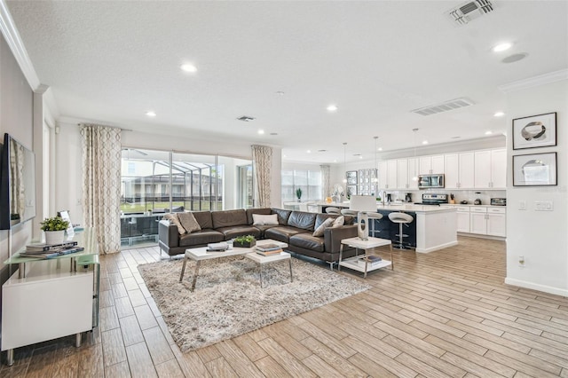 living room with visible vents, plenty of natural light, and ornamental molding