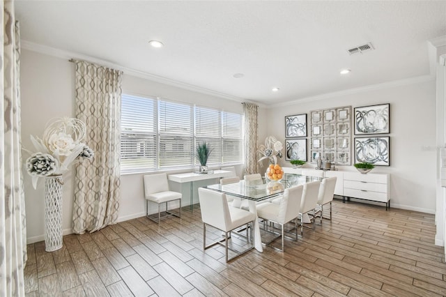 dining space with visible vents, crown molding, baseboards, and wood finished floors