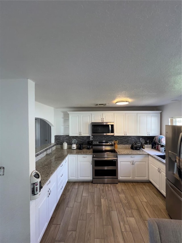 kitchen with dark wood-style floors, backsplash, and stainless steel appliances