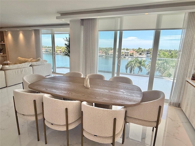 dining space with marble finish floor and a water view