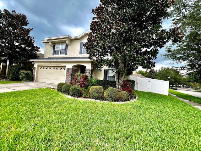 view of front of home featuring stucco siding, driveway, stone siding, fence, and a garage