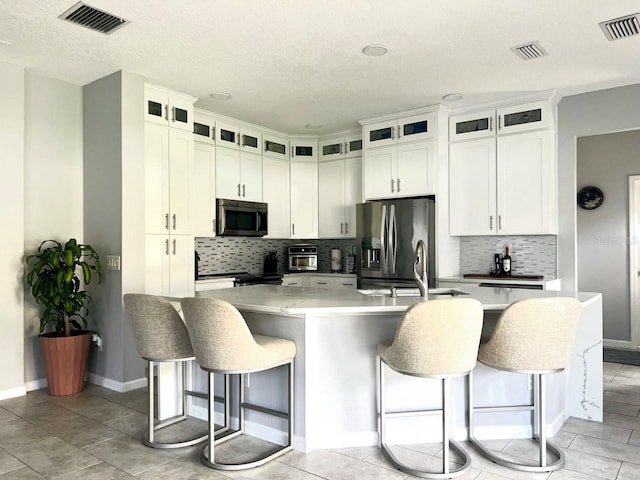 kitchen with visible vents, a kitchen breakfast bar, stainless steel appliances, and a sink