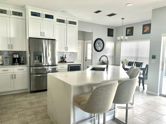 kitchen with a sink, visible vents, tasteful backsplash, and stainless steel fridge with ice dispenser