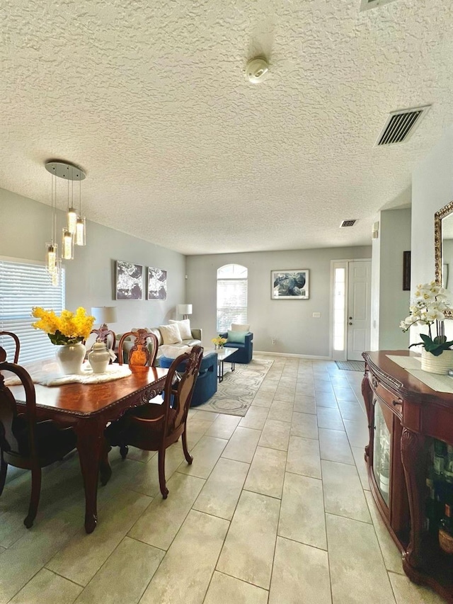 dining area with light tile patterned floors, visible vents, and a textured ceiling