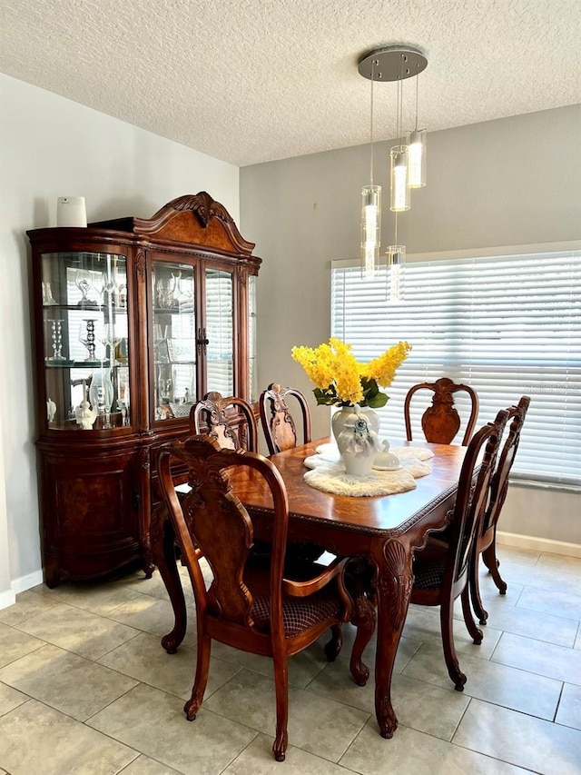 dining space with light tile patterned floors, baseboards, and a textured ceiling