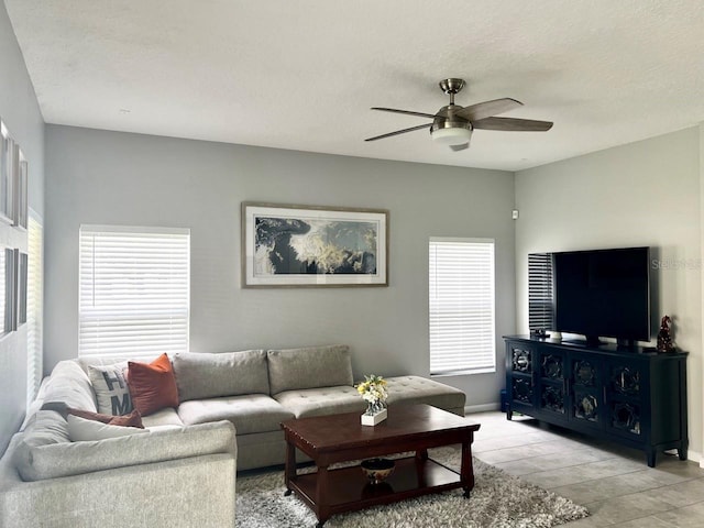 living area featuring baseboards, a textured ceiling, light wood-style floors, and a ceiling fan