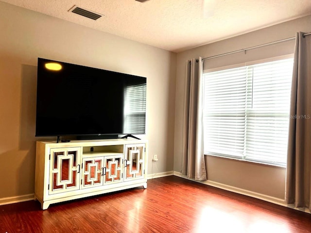 unfurnished living room featuring visible vents, a healthy amount of sunlight, and wood finished floors