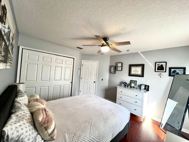 bedroom with visible vents, dark wood-type flooring, a closet, a textured ceiling, and a ceiling fan