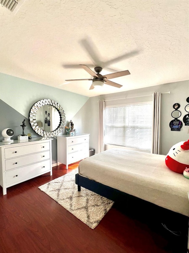 bedroom with visible vents, a textured ceiling, dark wood-style floors, and a ceiling fan