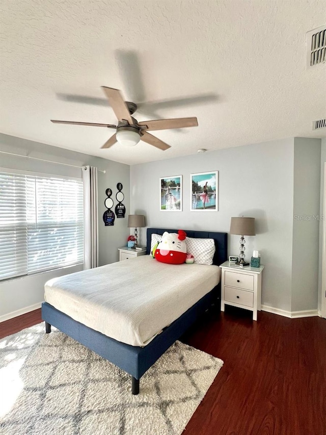 bedroom with wood finished floors, visible vents, and baseboards