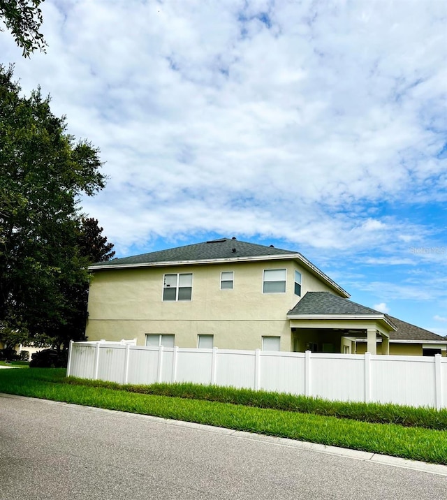 view of side of property featuring stucco siding and fence