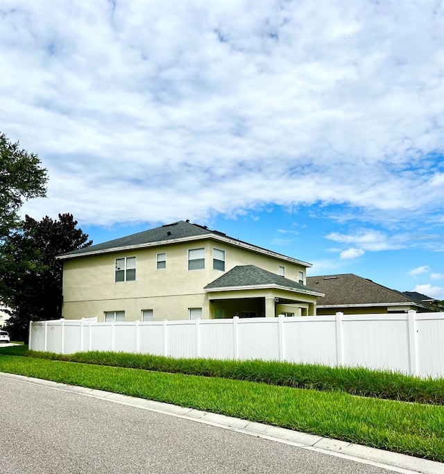 view of home's exterior with stucco siding and fence