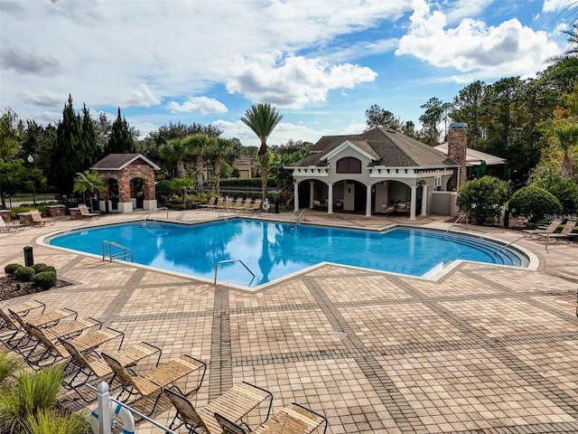 community pool with a patio area and fence