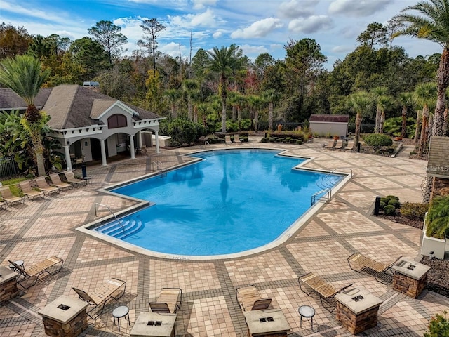 pool with fence, an outdoor structure, and a patio area