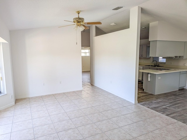 unfurnished living room featuring visible vents, baseboards, ceiling fan, lofted ceiling, and light tile patterned floors