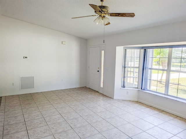 empty room featuring a textured ceiling, baseboards, visible vents, and ceiling fan