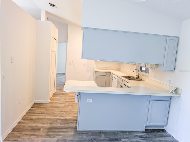 kitchen featuring visible vents, wood finished floors, light countertops, and a sink