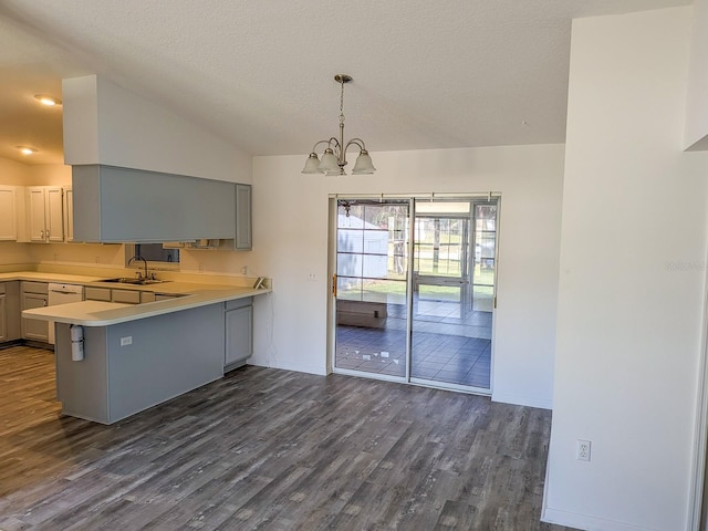 kitchen with an inviting chandelier, lofted ceiling, a sink, light countertops, and dark wood-type flooring