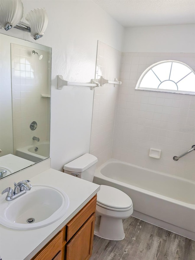 full bath with toilet, shower / tub combination, vanity, wood finished floors, and a textured ceiling