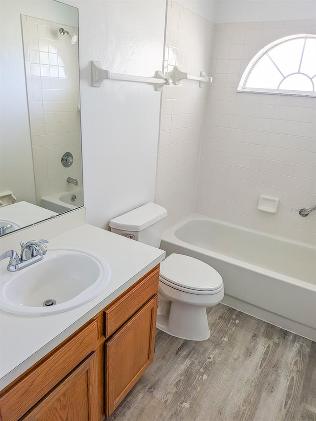 bathroom featuring vanity, toilet, wood finished floors, and shower / bathtub combination