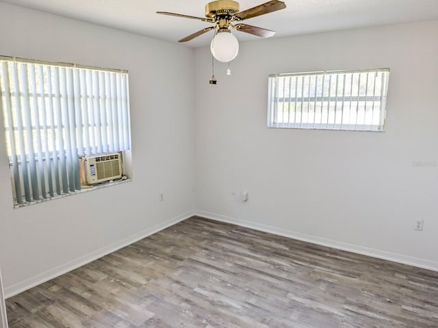 spare room featuring wood finished floors, cooling unit, a ceiling fan, and baseboards