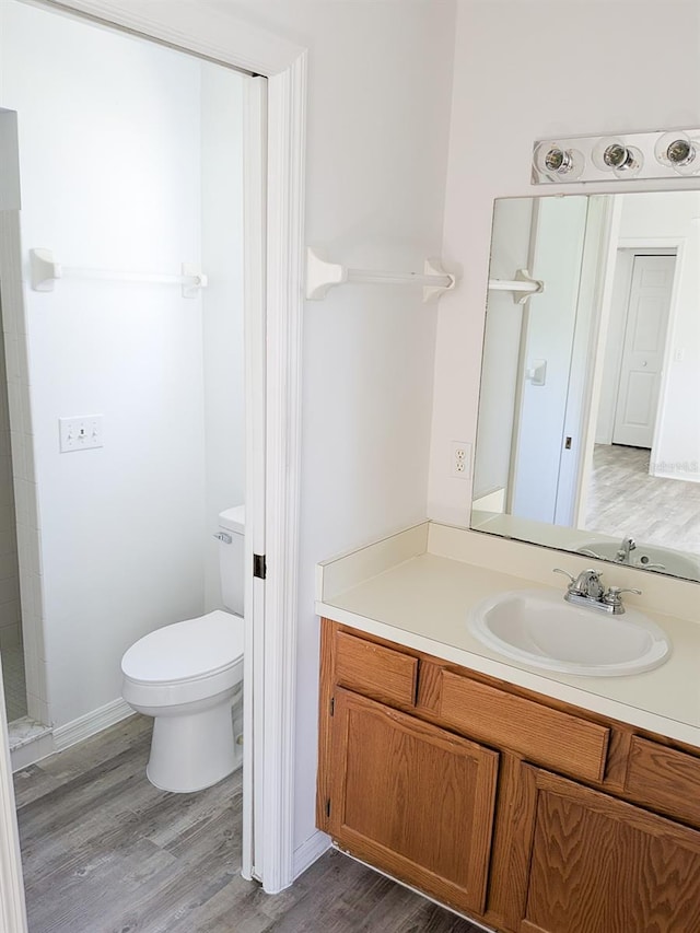 full bath with toilet, vanity, and wood finished floors