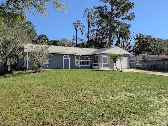 single story home featuring stucco siding, driveway, a front yard, a sunroom, and a garage