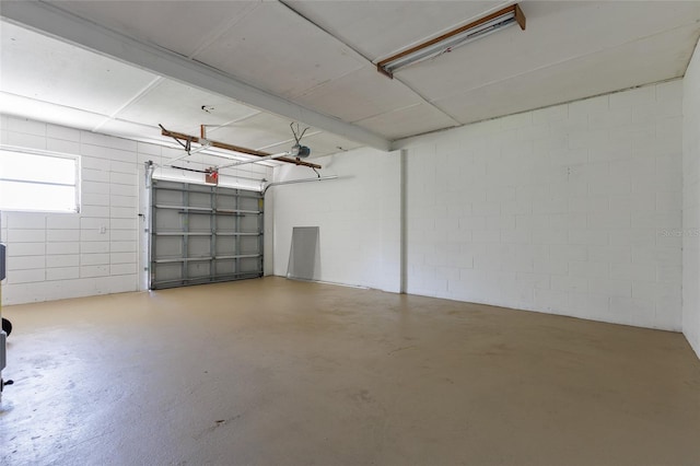 garage featuring concrete block wall and a garage door opener