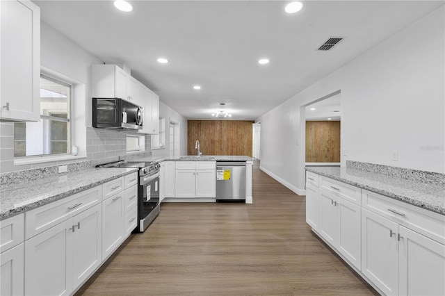 kitchen with visible vents, tasteful backsplash, stainless steel appliances, light wood-style floors, and a peninsula