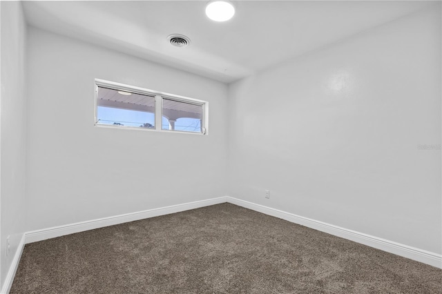 unfurnished room featuring visible vents, baseboards, and dark carpet