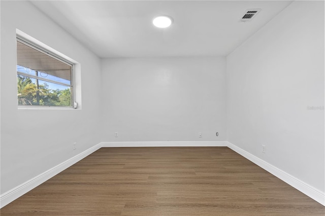 unfurnished room with wood finished floors, visible vents, and baseboards