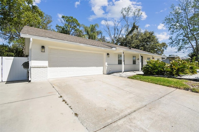 ranch-style home with a gate, fence, driveway, a garage, and brick siding