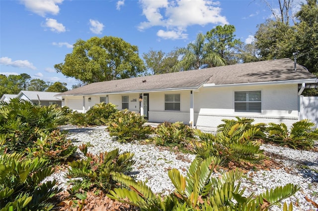 single story home with brick siding, stucco siding, a shingled roof, and a garage