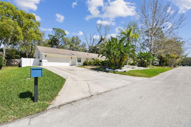 single story home featuring fence, driveway, an attached garage, stucco siding, and a front lawn