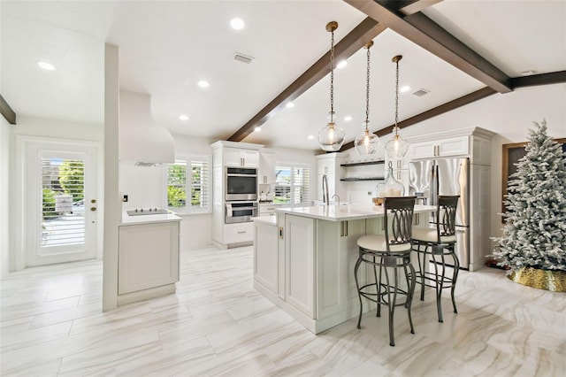 kitchen featuring visible vents, vaulted ceiling with beams, extractor fan, appliances with stainless steel finishes, and a kitchen bar