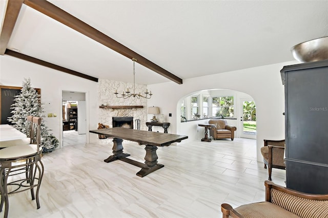 dining room featuring arched walkways, a stone fireplace, vaulted ceiling with beams, and a chandelier