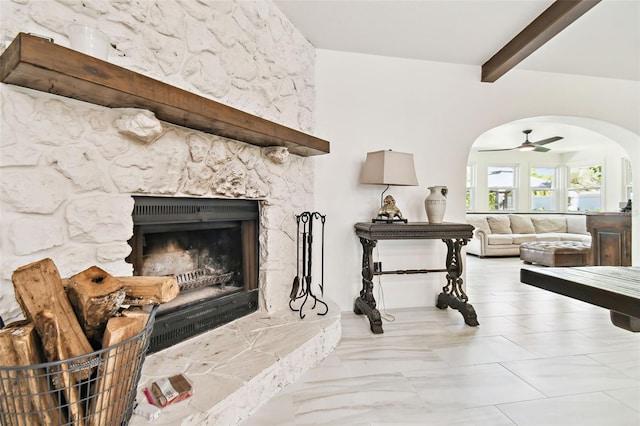 interior space with arched walkways, a stone fireplace, beamed ceiling, and a ceiling fan