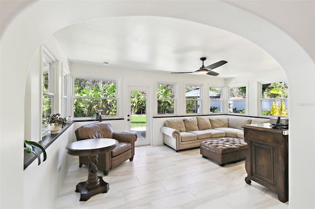 sunroom / solarium featuring arched walkways and a ceiling fan