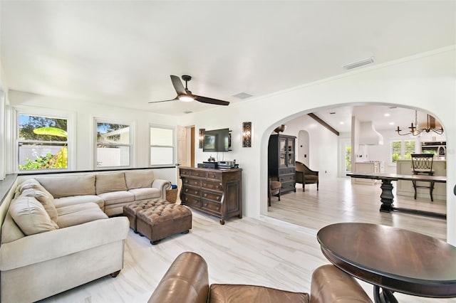 living room featuring ceiling fan with notable chandelier, visible vents, arched walkways, and ornamental molding