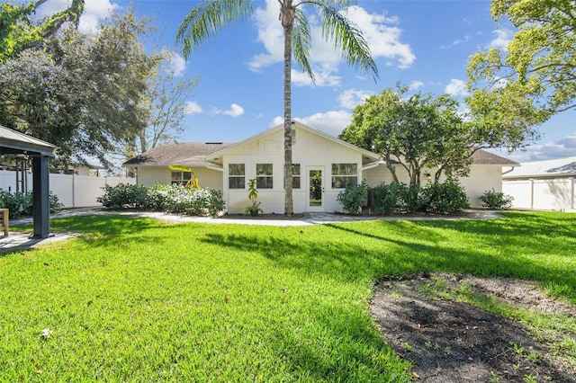 back of property featuring a gazebo, a lawn, and fence