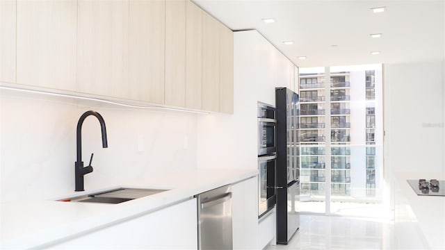 kitchen featuring light countertops, modern cabinets, appliances with stainless steel finishes, and a sink