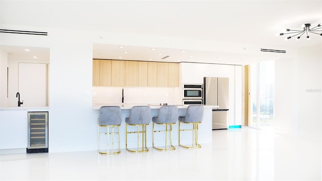 kitchen featuring modern cabinets, beverage cooler, a breakfast bar, stainless steel appliances, and light countertops