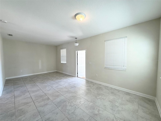 spare room with visible vents, baseboards, and a textured ceiling