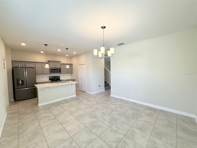 kitchen with visible vents, a kitchen island with sink, gray cabinetry, light countertops, and appliances with stainless steel finishes