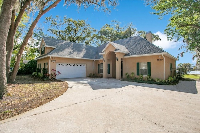 view of front facade featuring fence, a chimney, stucco siding, concrete driveway, and a garage