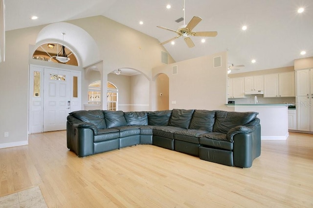 living room with visible vents, ceiling fan, light wood-style flooring, arched walkways, and high vaulted ceiling