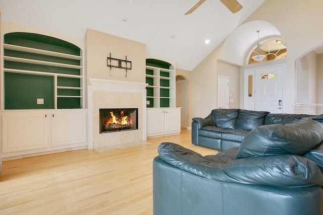 living area with a fireplace, high vaulted ceiling, wood finished floors, and ceiling fan